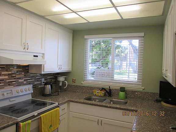 White Lacquer kitchen cabinents; granite counter tops. This photo is dated, there are LED down lights now and the flourescent drop is gone.