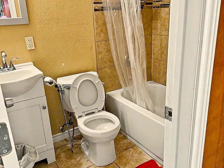 Full bathroom with a tiled tub/shower combo, vanity with mirror, and easy-clean tile flooring for everyday convenience.