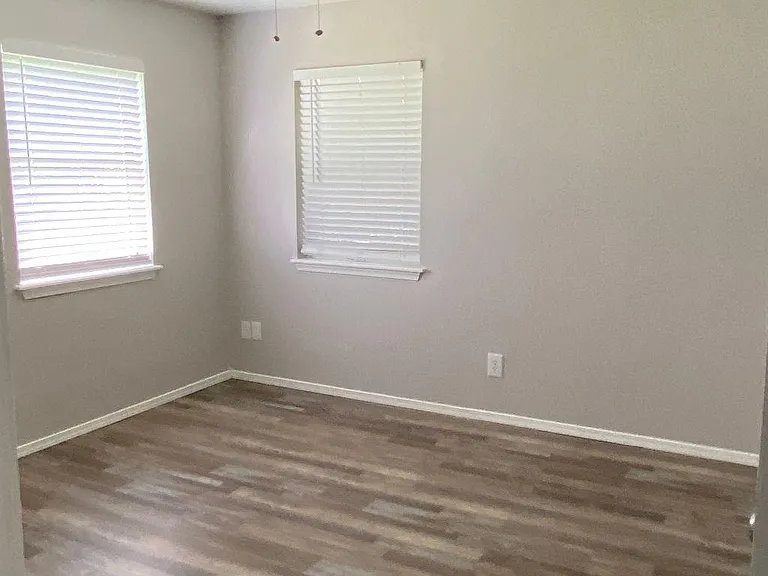 Corner bedroom with ceiling fan and new blinds.