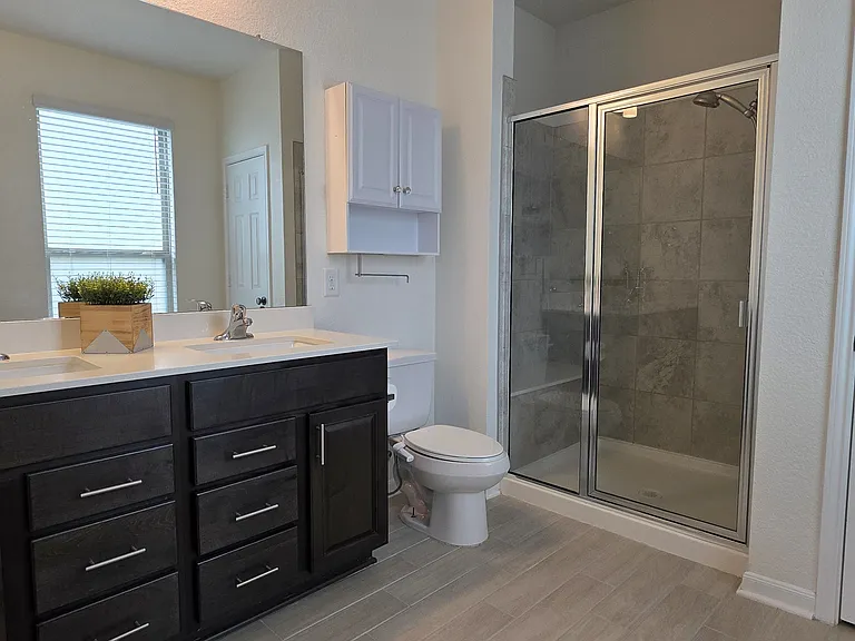 Main bathroom features dual sinks, a spacious vanity, and a walk-in shower.