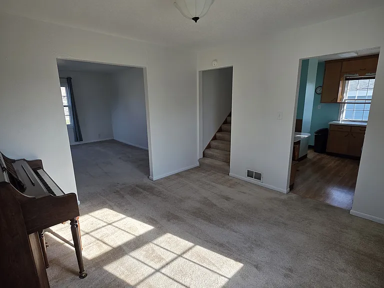 View from dining room toward kitchen, living room, and stairway.