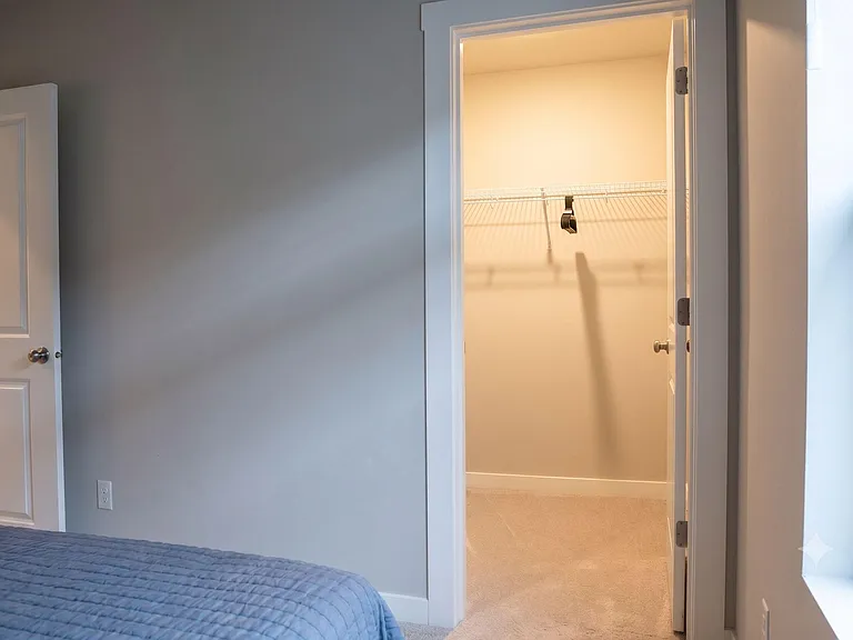Bedroom with a reach-in closet featuring wire shelving and carpeted floors, plus a window for natural light.