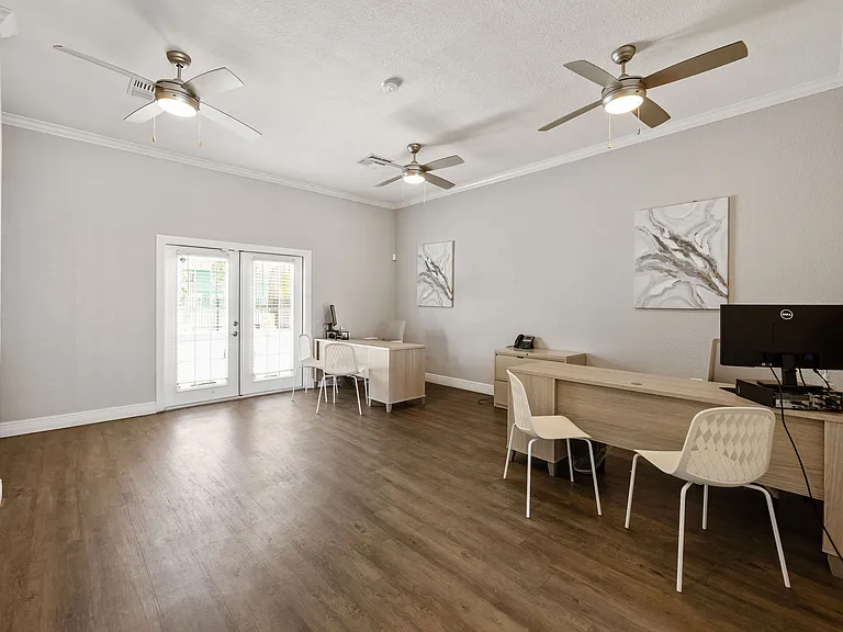 Bright and modern office space featuring sleek desks, comfortable seating, and elegant ceiling fans, perfect for productivity.