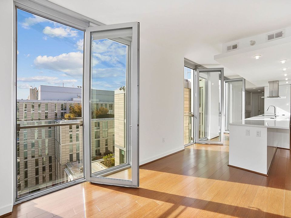 Bright and contemporary apartment with expansive glass doors, offering stunning urban views and a minimalist kitchen design.