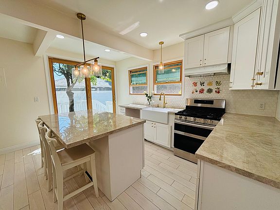 View of the kitchen island, farmer's sink, double oven, sliding doors and matching twin windows over the sink & counter facing private side yard.