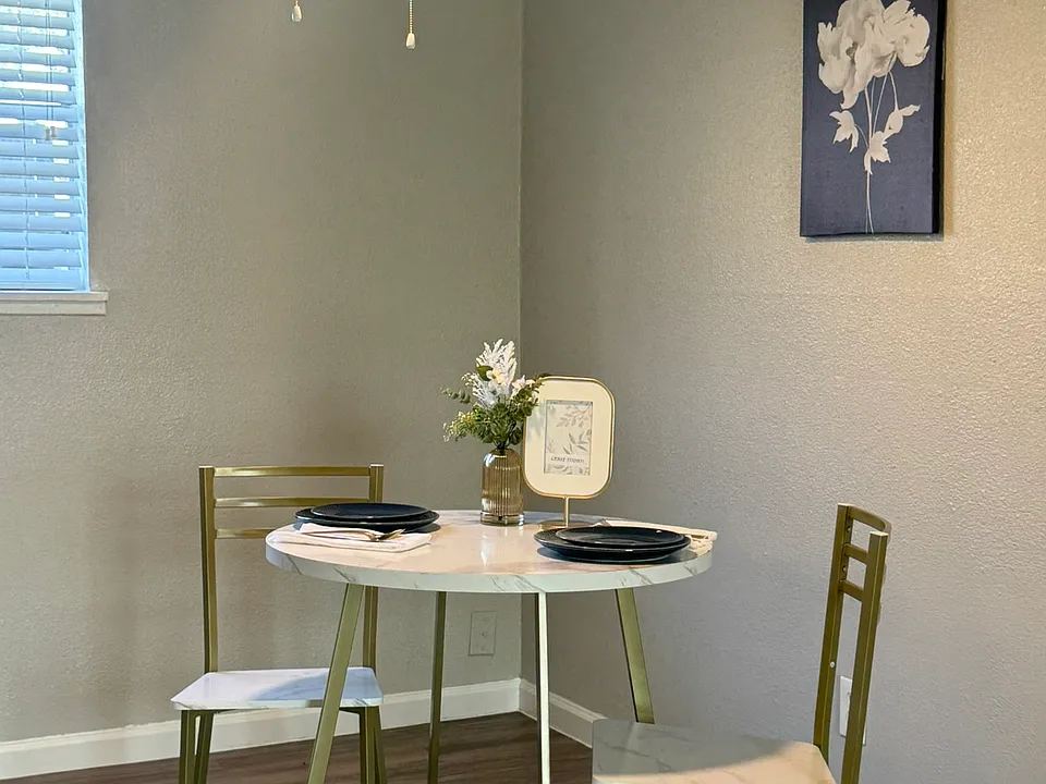 This inviting dining area features warm natural light and a contemporary ceiling fan that enhances the clean, updated design.