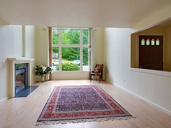 View of the front door entry to the right, and wall of windows flooding the living space with natural light.