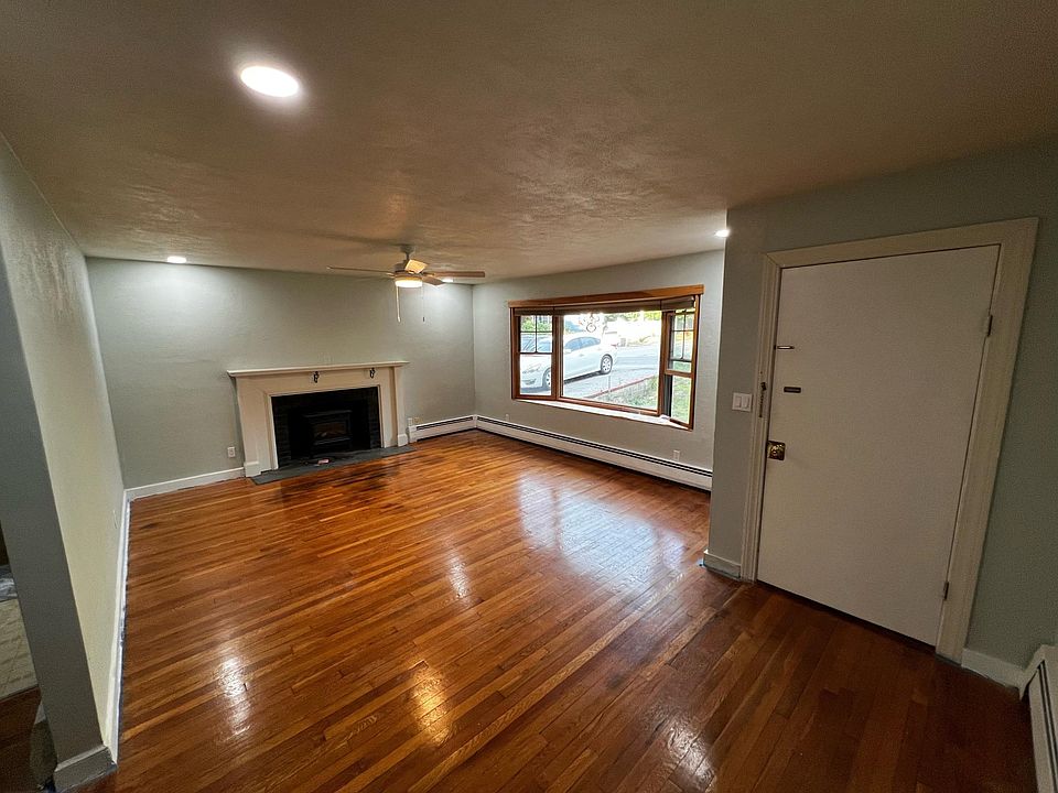 Big spacious living room with a fake fireplace and big window with a view of the front yard