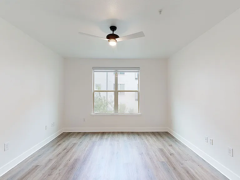 Spacious apartment bedroom with wood-style flooring.
