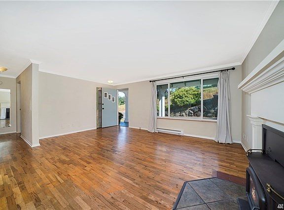Living room with original wood flooring and insert fireplace.  Good sized room that offers large window not natural lighting.