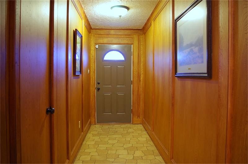 Long entryway lined with beautiful solid wood block paneling.