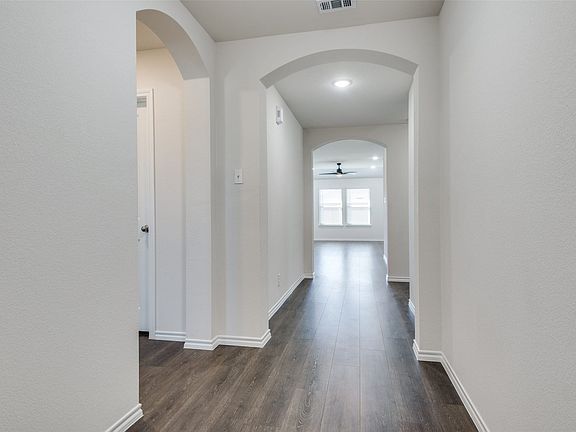 Hallway featuring wood-finish flooring, arched doorways, white trim, and recessed lighting