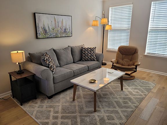 Bright and cozy living room with new sofa, rug, coffee table, end tables.