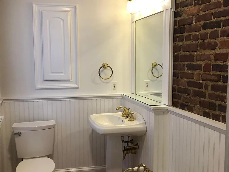 First floor full bath with deep old fashioned bathtub. Original exposed brick.