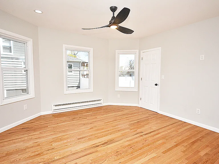Living room - beautiful new hardwood floors, bay windows, lighted ceiling fan, and closet door. Outlet on wall perfect for wall mounted TV.