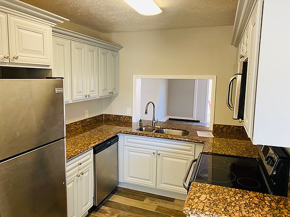 Marble top kitchen with stainless steel appliances (dishwasher, microwave, stove and fridge).