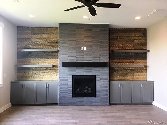 Large great room on upper floor sits open to the kitchen and nook space.  Gas fireplace with built in cabinets, shelving, mantle