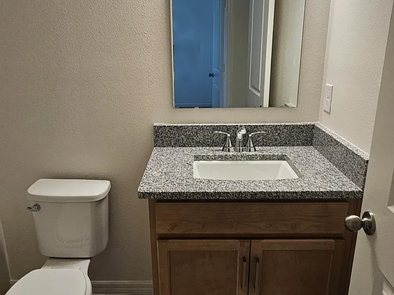 Full hallway bathroom featuring granite countertop vanity, tub/shower combination, and modern lighting.