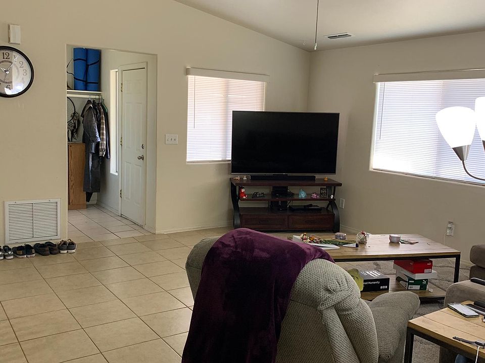 Living area with ceiling fan and closet in entry hall