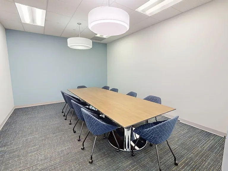 Modern conference room with a sleek wooden table, stylish chairs, and elegant lighting, ideal for productive meetings.
