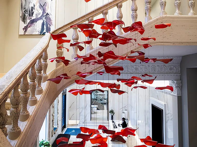 Preserved grand staircase, seen in the original architectural accent photos, now features modern hanging art