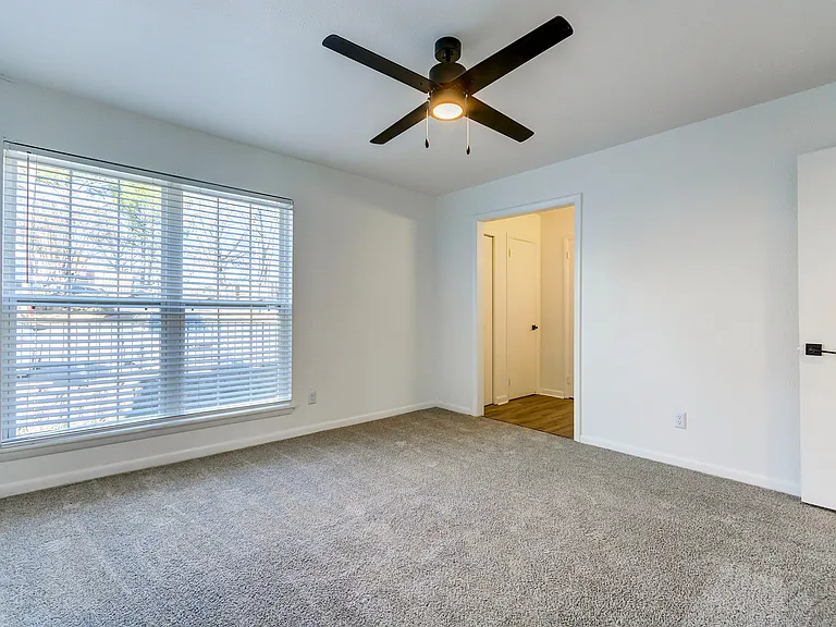 A carpeted bedroom with oversized closet and ceiling fan is shown at ReNew on Cantrell.
