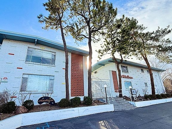 Charming apartment complex with retro architecture, surrounded by lush trees and well-maintained landscaping.