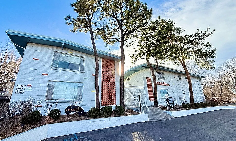 Charming apartment complex with retro architecture, surrounded by lush trees and well-maintained landscaping.