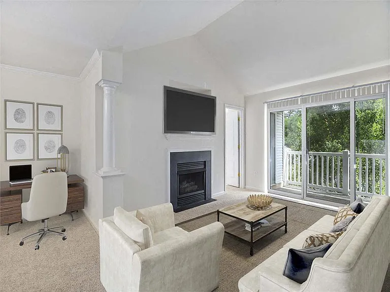 Classic living room with a fireplace and lovely wooded views from the private balcony at The Crossings at Russett in Laurel, MD