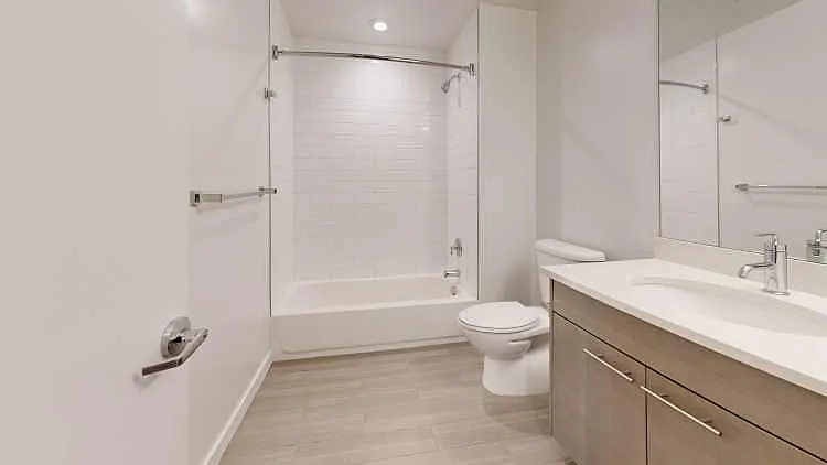 Apartment bathroom with wood-style flooring.