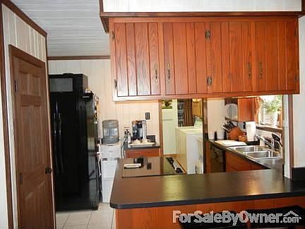 Kitchen from hallway
						:
						Another view of kitchen highlights black appliances and custom cabinets.