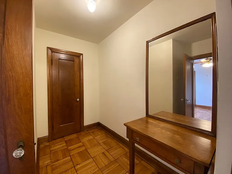 Tucked right off of the main room - this dressing room showcases warm parquet hardwood floors, original woodwork, and a classic built-in vanity with mirror. You will also find the third closet for the unit.