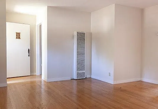 Living room facing the open front door, showing the wall heater