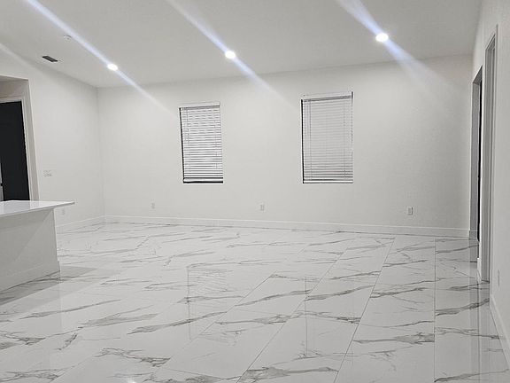 Expansive Open Living Area with Two Large Windows, Recessed Lighting, and Beautiful Marble-Look Tile Flooring
