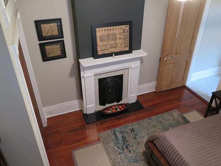 Stylish and comfortable bedroom with new rugs, newsprint art and original fireplace.