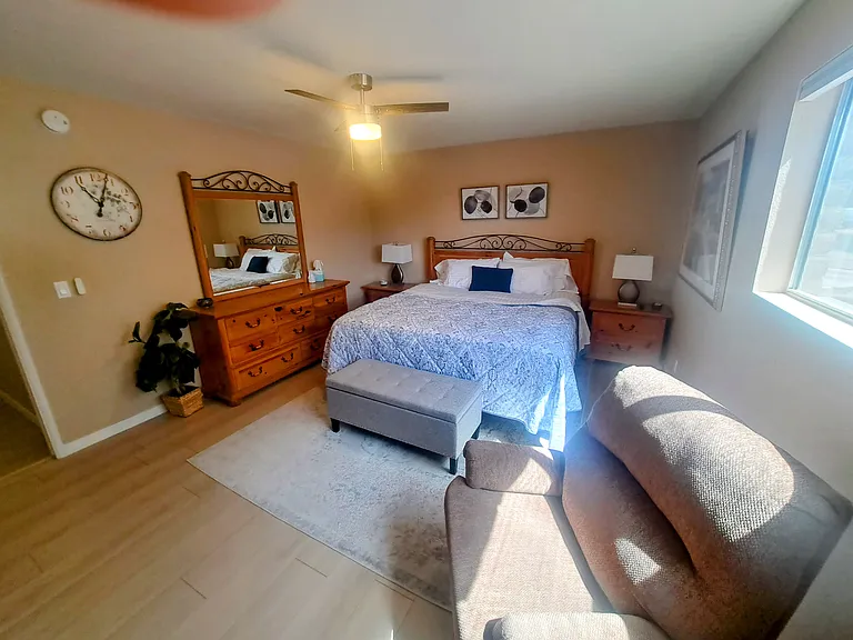 Large master bedroom with king bed, tv, 2 nightstands, large dresser, and recliner