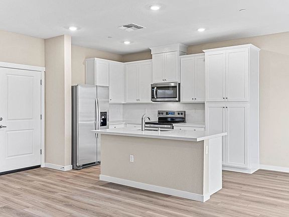 The kitchen has stainless steel appliances and plank flooring.