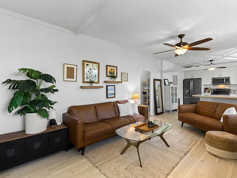 The living room includes an Italian leather sofa and loveseat and one chair, TV, ceiling fan, windows and an AC unit. The living room opens to the lanai and blends seamlessly with the kitchen.