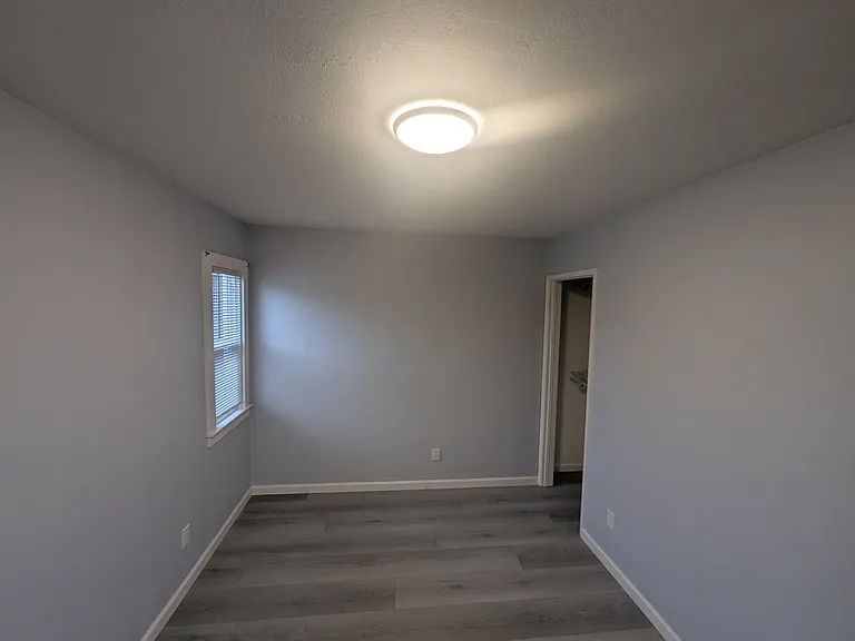 Bedroom looking at far back window and closet.