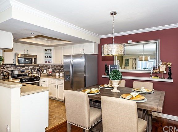 Dining area open to kitchen with modern light fixture.