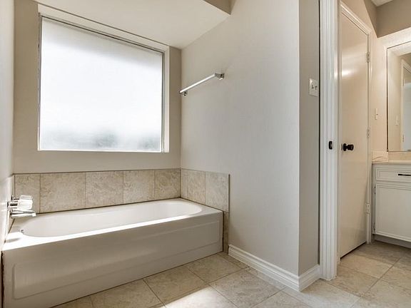 Tub with frosted window in the master bathroom. Porcelain tile throughout.