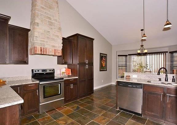 Brick/Stone range hood accents the custom cabinets, granite, stainless appliances and slate flooring. Under cabinet and Recess lighting compliment this kitchen.
