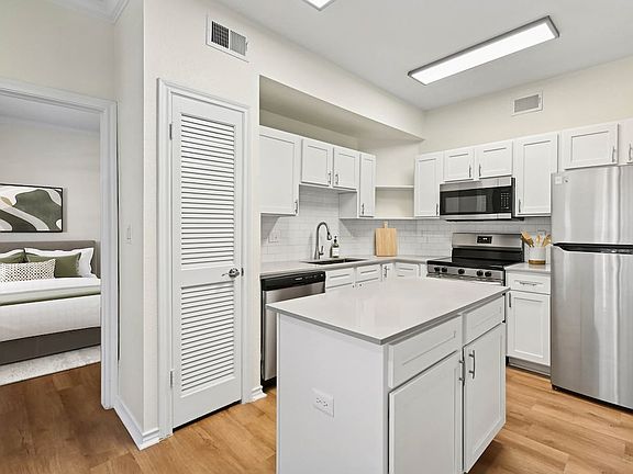 Renovated Package I kitchen with stainless steel appliances, white cabinetry, white tile backsplash, grey quartz countertops, and hard surface flooring