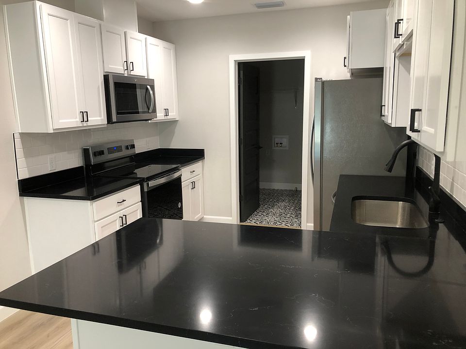 Kitchen with stainless steel appliances and black quartz. White subway backsplash, and sink deposal