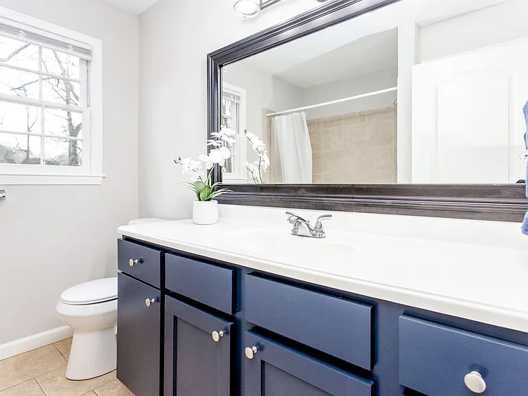 Shared upstairs bath with large vanity and closet for storage.