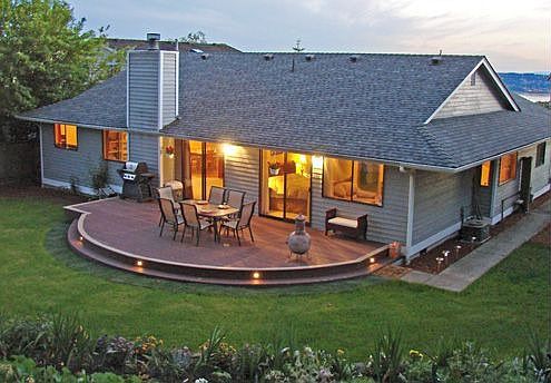 Back yard has a large lawn and three terraces with flowers. 