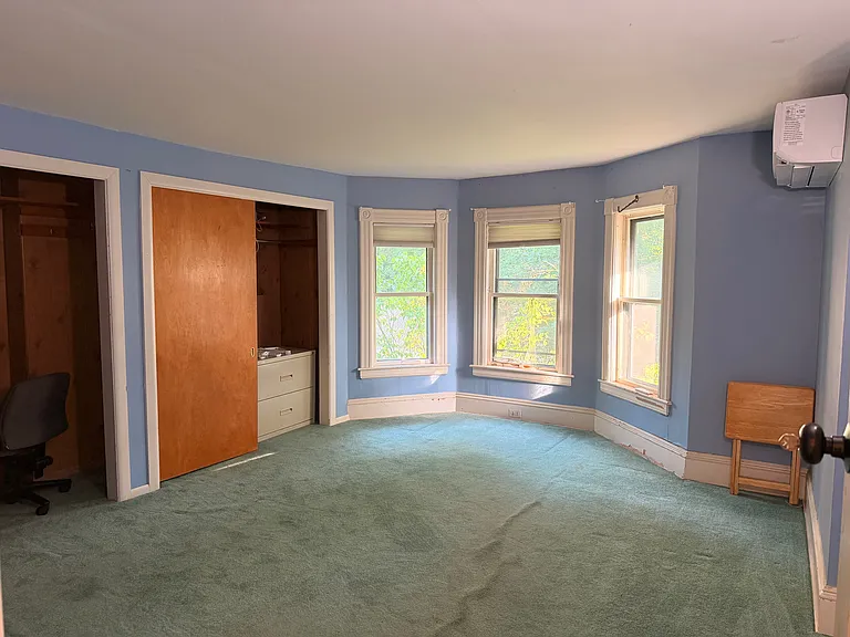 Upstairs side bedroom, showing heat pump, bay windows, closets.