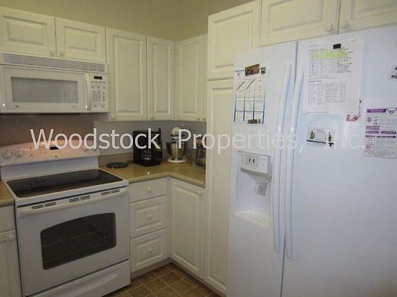 Cheerful kitchen, white cabinetry, electric cooktop/oven, microwave, side-by-side refrig w/water dispenser.