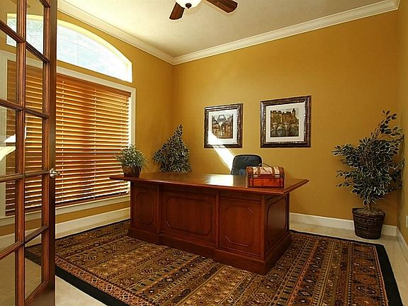 The office, located just off the entry has custom 8 ft wood stained French doors, high ceilings, custom crown molding, custom paint, large decorative fan, & 2 inch wood blinds.