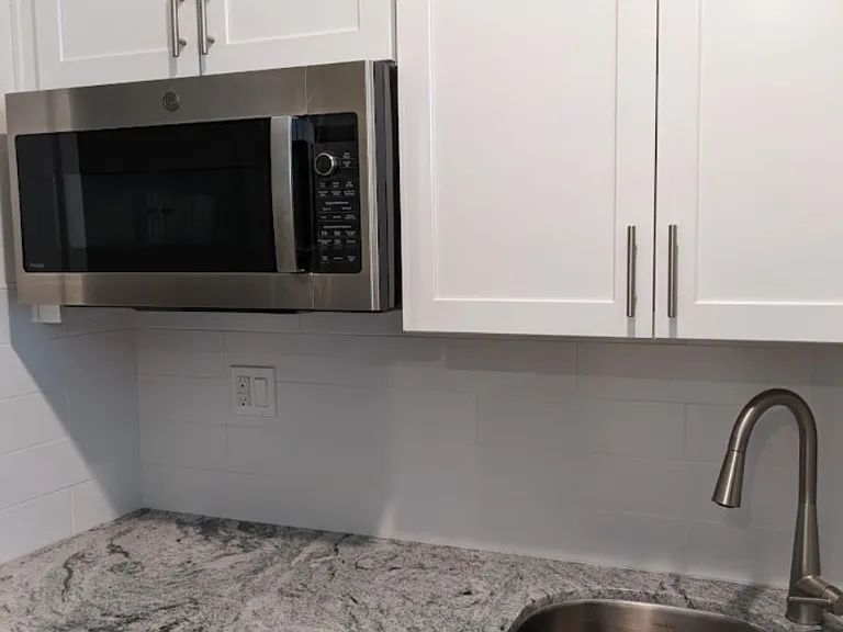 Modern kitchenette with abundant storage and premium, multi-function GE Profile convection microwave oven and a convenient garbage disposal. Designed for both form and function, this efficient workspace makes cooking and meal prep a breeze.